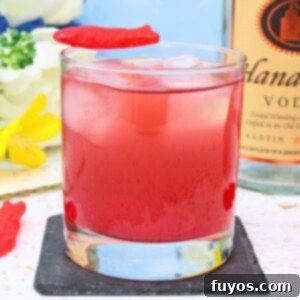 Vibrant Swedish Fish cocktail, garnished with candy, featured in a recipe card format.