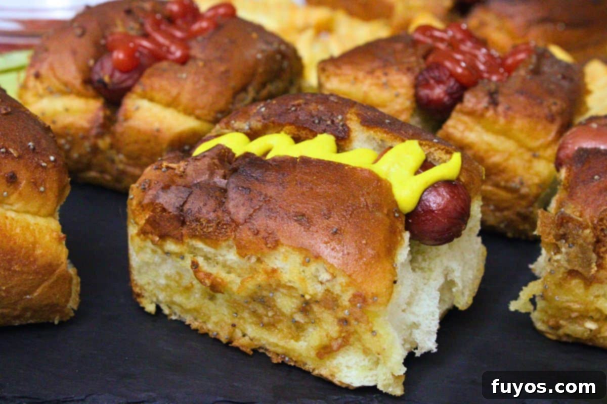 27 Irresistible Air Fryer Hot Dog Creations 18 closeup of a hot dog slider with a swirl of mustard and a brushed butter hawaiian roll bun