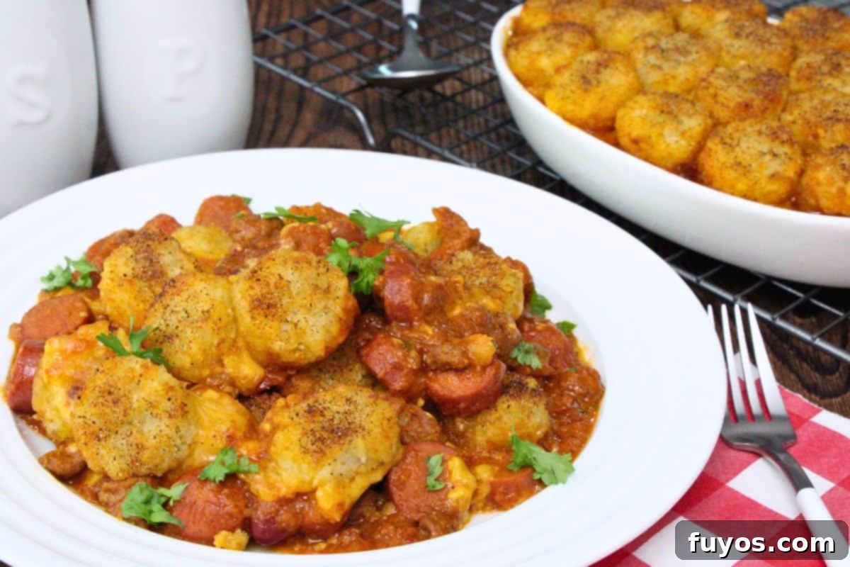 27 Irresistible Air Fryer Hot Dog Creations 25 plate with chili cheese hot dog casserole showing off crispy tater tots on top next to warm serving dish