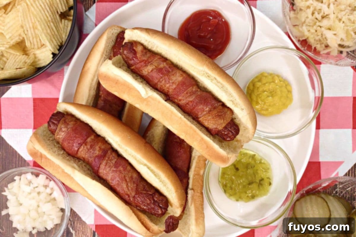 27 Irresistible Air Fryer Hot Dog Creations 5 overhead view of air fryer bacon wrapped hot dogs on a plate with ketchup and mustard
