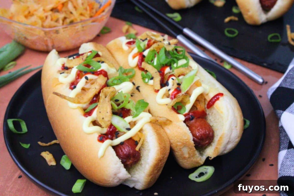 27 Irresistible Air Fryer Hot Dog Creations 7 two air fryer kimchi hot dogs with kewpie mayo and chopped green onions on a black plate