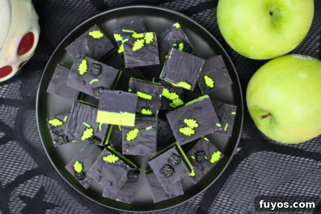 Poison Apple Fudge: A Hauntingly Easy No-Bake Treat 11 overhead view of poison apple fudge stacked on a black plate on black web lace cloth with fresh apples around