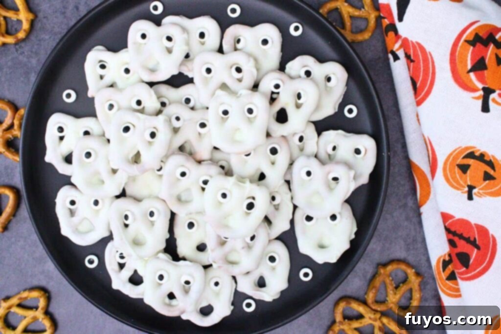 overhead view of ghost pretzels on a black plate next to a white napkin with pumpkins