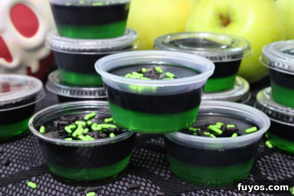 Poison Apple Jello Shots: An Adult Halloween Delight 11 closeup view of three poison apple jello shots stacked in a pyramid showing black and green layers