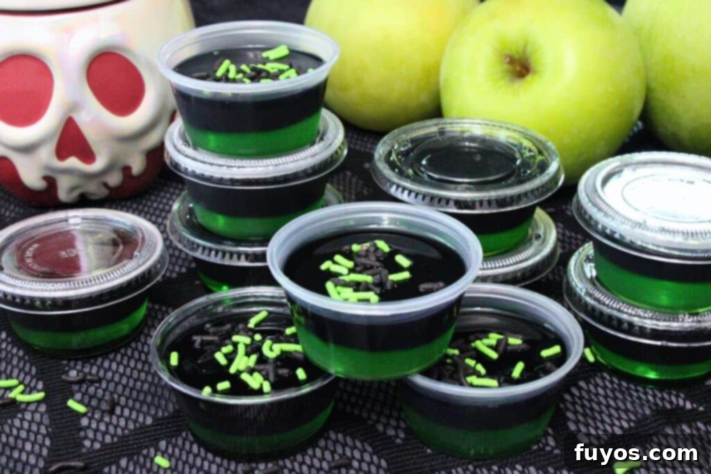 Poison Apple Jello Shots: An Adult Halloween Delight 3 several black and green poison apple jello shots topped with black and green sprinkles with fresh apples in the background