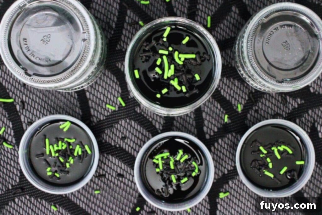 Poison Apple Jello Shots: An Adult Halloween Delight 10 overhead view of poison apple jello shots with black and green sprinkles on a black web lace mat