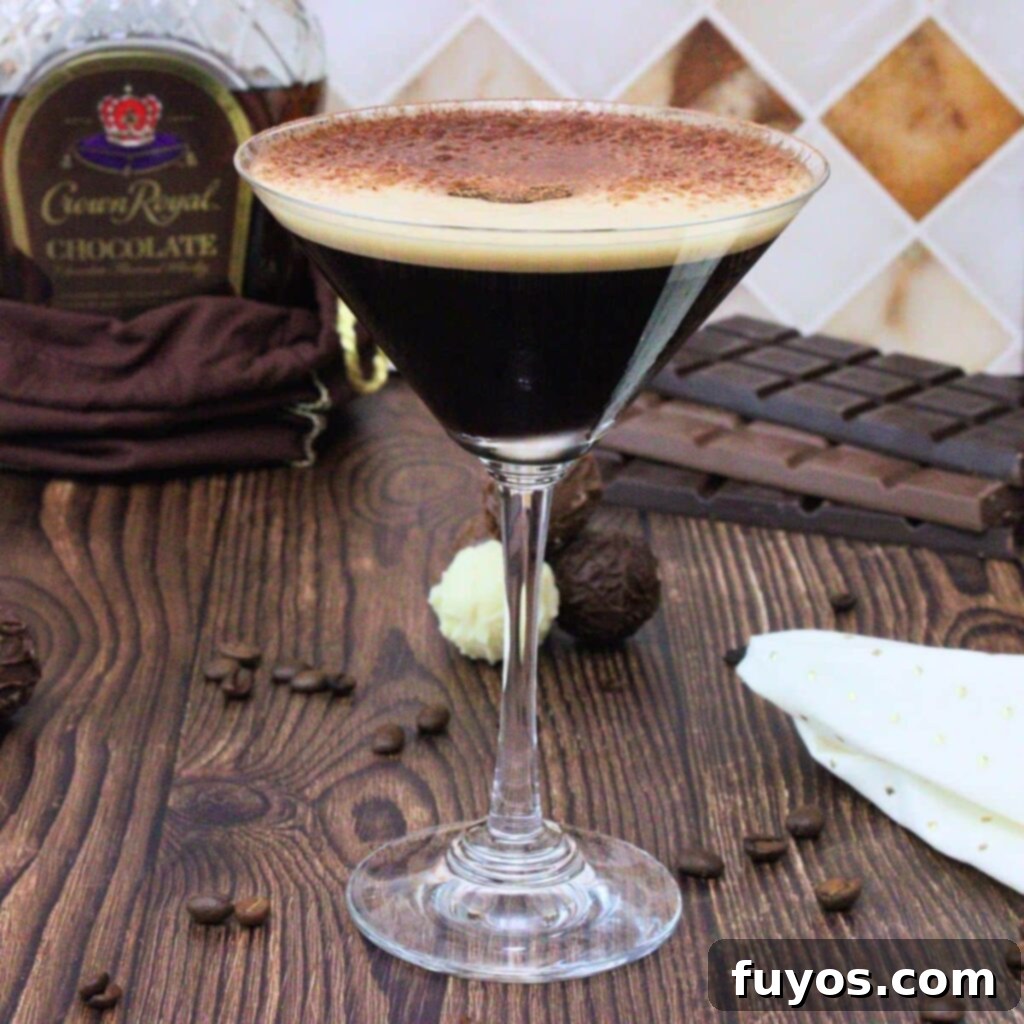 Velvet Crown Royal Espresso Chocolate Martini 2 A beautifully garnished chocolate espresso martini with a rich, dark hue, topped with a delicate dusting of cocoa powder and three coffee beans, against a soft, inviting background, ready to be enjoyed.