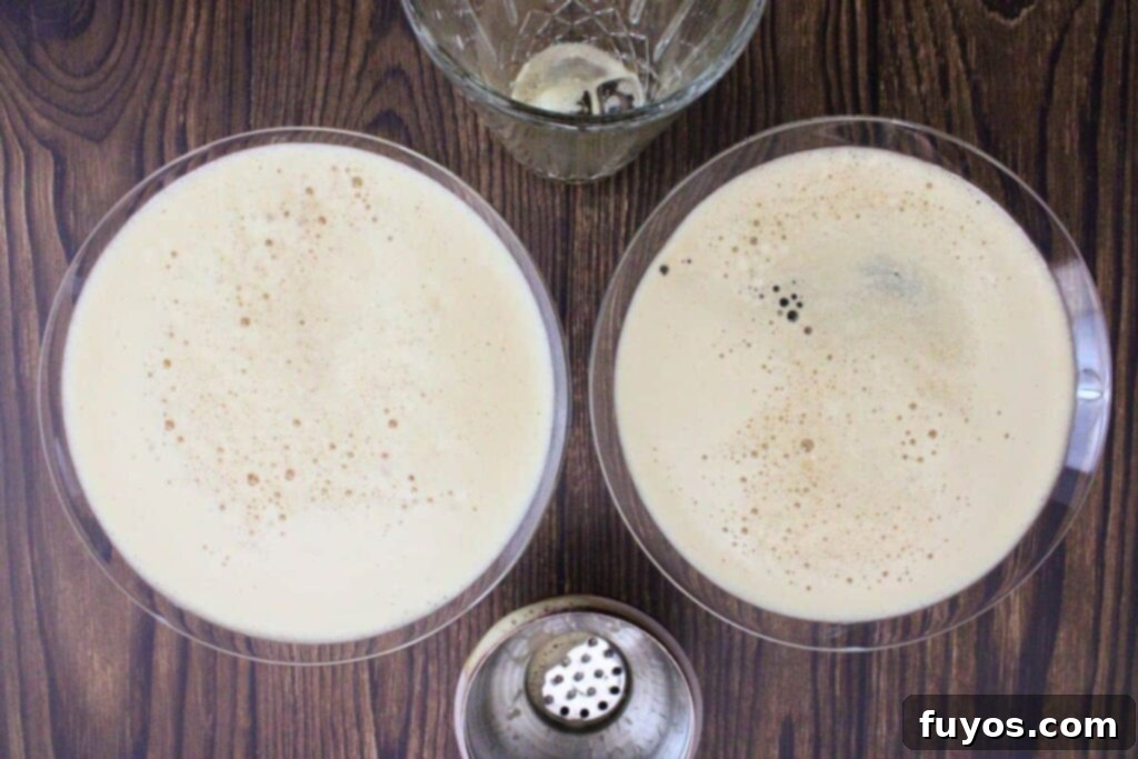 Velvet Crown Royal Espresso Chocolate Martini 6 A frothy chocolate espresso martini being strained from a cocktail shaker into a chilled martini glass, showcasing the creamy texture and rich color of the drink.