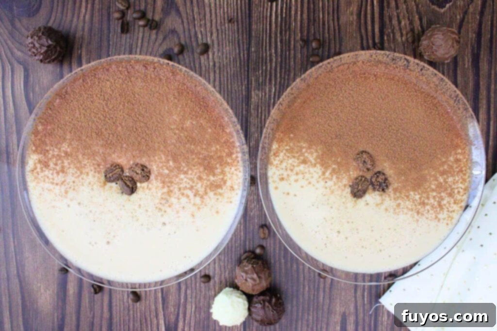 Velvet Crown Royal Espresso Chocolate Martini 7 An inviting overhead view of two perfectly prepared chocolate espresso martini drinks, each elegantly dusted with cocoa powder and adorned with three coffee beans, presented in classic martini glasses.