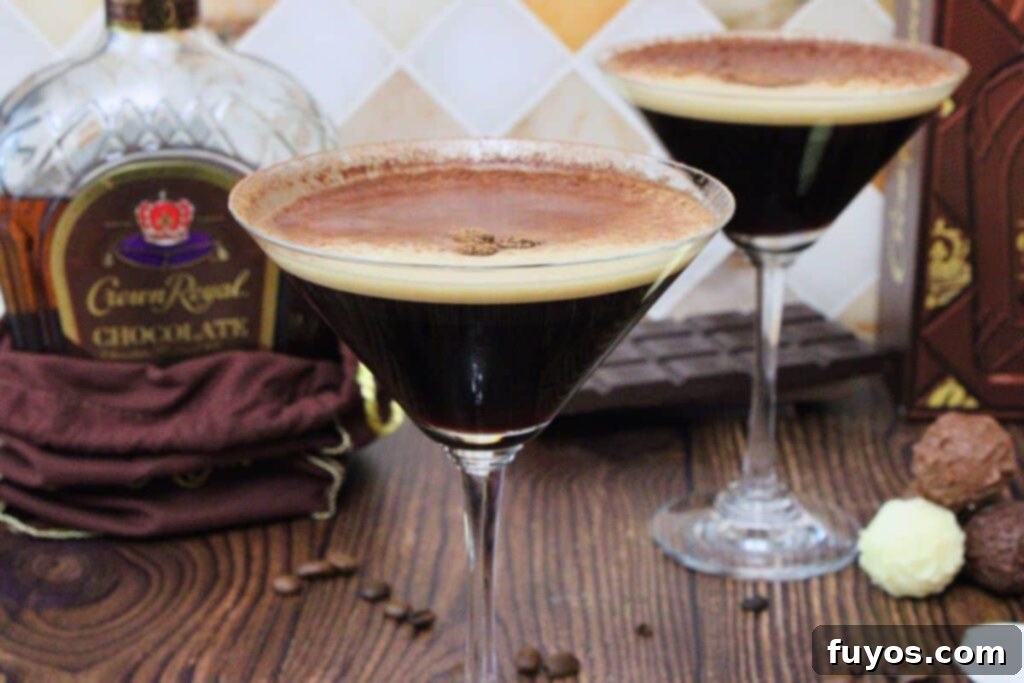 Velvet Crown Royal Espresso Chocolate Martini 8 A close-up of a perfectly garnished chocolate espresso martini, with a second martini and a bottle of Crown Royal chocolate whisky softly blurred in the background, highlighting the drink's rich appeal.