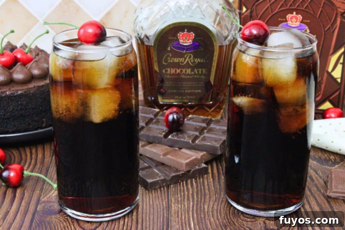 two crown royal chocolate and cherry coke drinks garnished with cherry in front of crown bottle