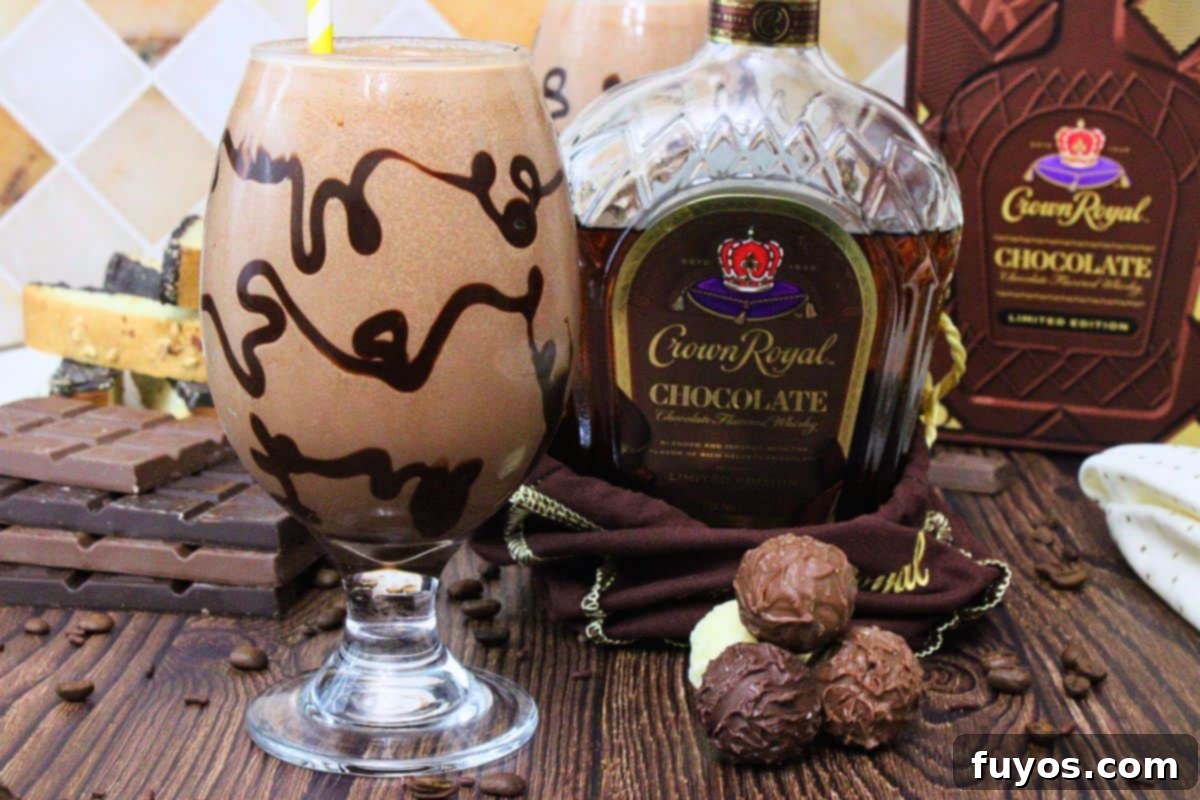 chocolate mudslide with chocolate drizzle in the glass next to chocolate crown royal bottle and chocolate candies