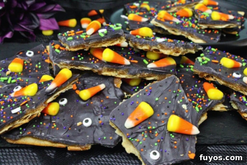 No Bake Halloween Saltine Crack Toffee 11 Sweet Halloween crack with candy corn and candy eyes overflowing on a black slate platter, showcasing the festive decorations.