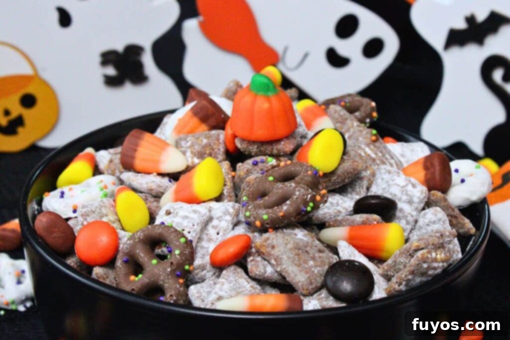 Mummy's Muddy Munch 10 closeup view of halloween puppy chow in a dark bowl showing off candy corn and candy corn pumpkins in chocolate chex mix