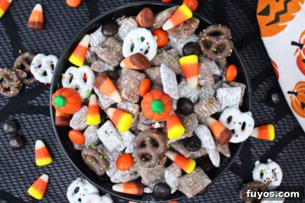 Mummy's Muddy Munch 9 overhead view of halloween puppy chow in a bowl with more chocolate and candies spread over a black counter