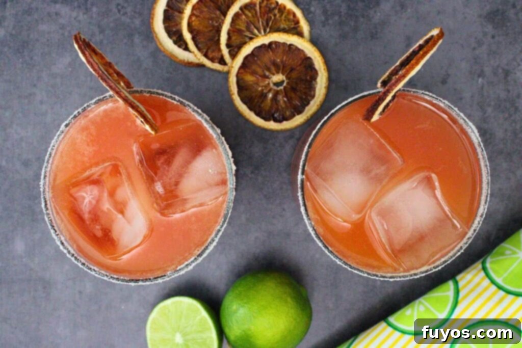 Blood Orange Margaritas The Perfect Spooky Cozy Sip 8 overhead view of two blood orange margarita cocktails with sugar rim and blood orange slice on dark counter