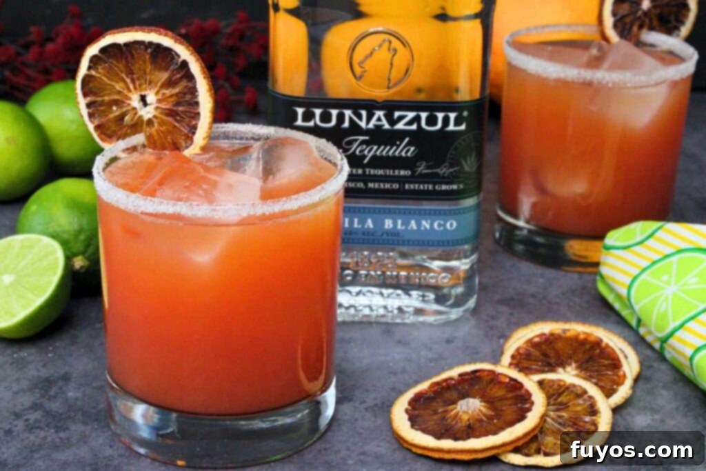 Blood Orange Margaritas The Perfect Spooky Cozy Sip 9 two blood orange margaritas garnished with blood orange slice around tequila bottle and fresh limes