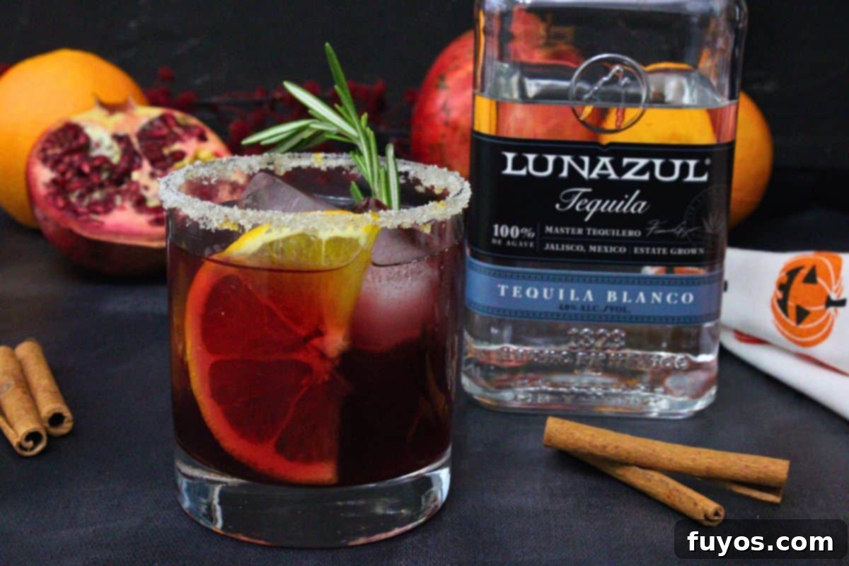 11 Easy Tequila Cocktails: Spooktacular Sips for Halloween 4 sleepy hollow cocktail with orange slice and rosemary garnish next to tequila bottle against a dark background