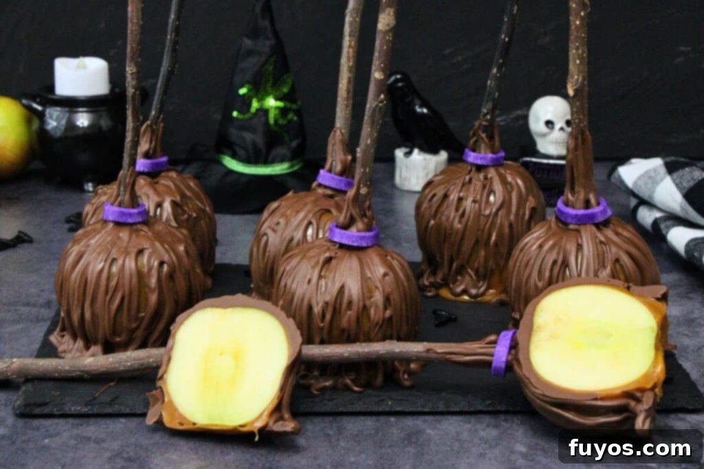 No-Bake Caramel Apple Broomsticks 11 several caramel apple broomsticks with wooden twig handles on a piece of slate and one laying down cut in half to show the apple