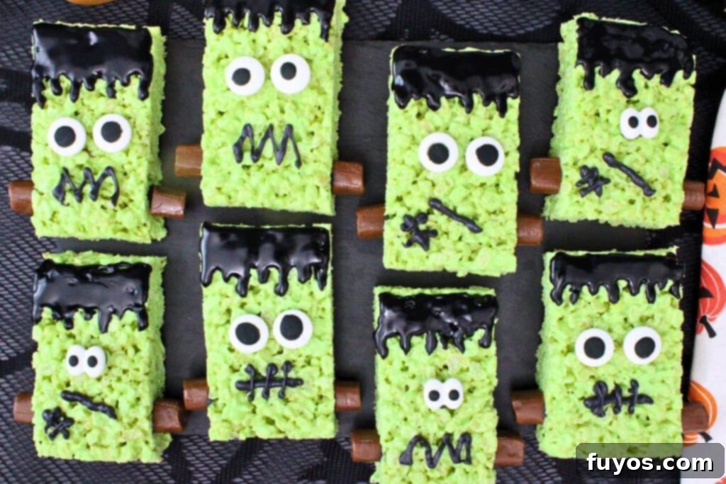 Conjure Up Frankenstein Krispie Monsters: No-Bake Halloween Magic 11 overhead view of several green frankenstein rice krispie treats with icing face candy eyes and tootsie rolls on piece of slate
