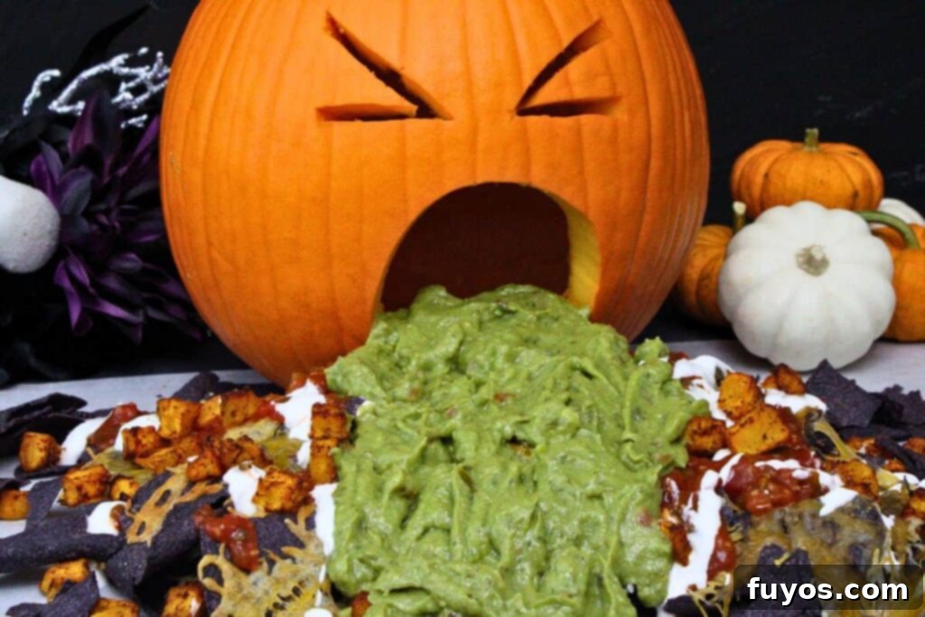 Air Fryer Halloween Monster Pumpkin Nachos 11 halloween puking pumpkin nachos with guacamole on top of blue tortilla chips with salsa, cheese, diced pumpkin, and sour cream