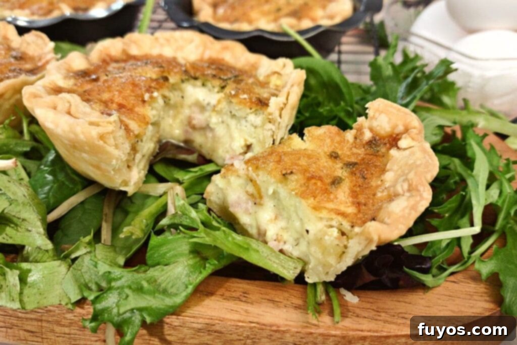 triangle slice of ham and cheese cheese quiche cut out and sitting next to the rest of the mini quiche