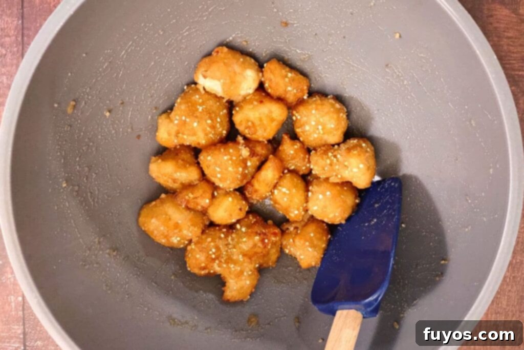air fryer cauliflower being mixed with buffalo sauce in a bowl
