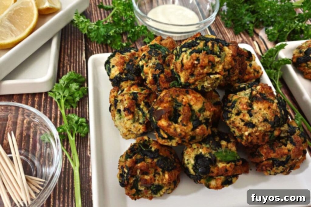 Crispy Air Fryer Spinach Bites 3 spinach balls on a square plate piled up in a pyramid on the right with lemon wedges and toothpicks on the left
