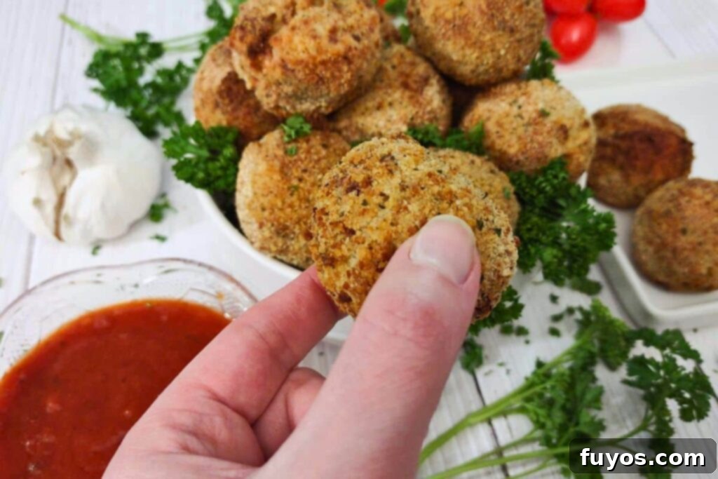 Crispy Air Fryer Arancini Mozzarella Stuffed Rice Balls 3 holding up an air fried arancini rice ball, showing its perfectly crispy crust