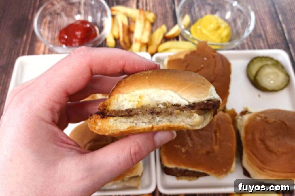 Quick and Easy Air Fried White Castle Sliders From Frozen 3 Hand holding a freshly air-fried White Castle slider, showing its perfectly crispy bun and juicy patty