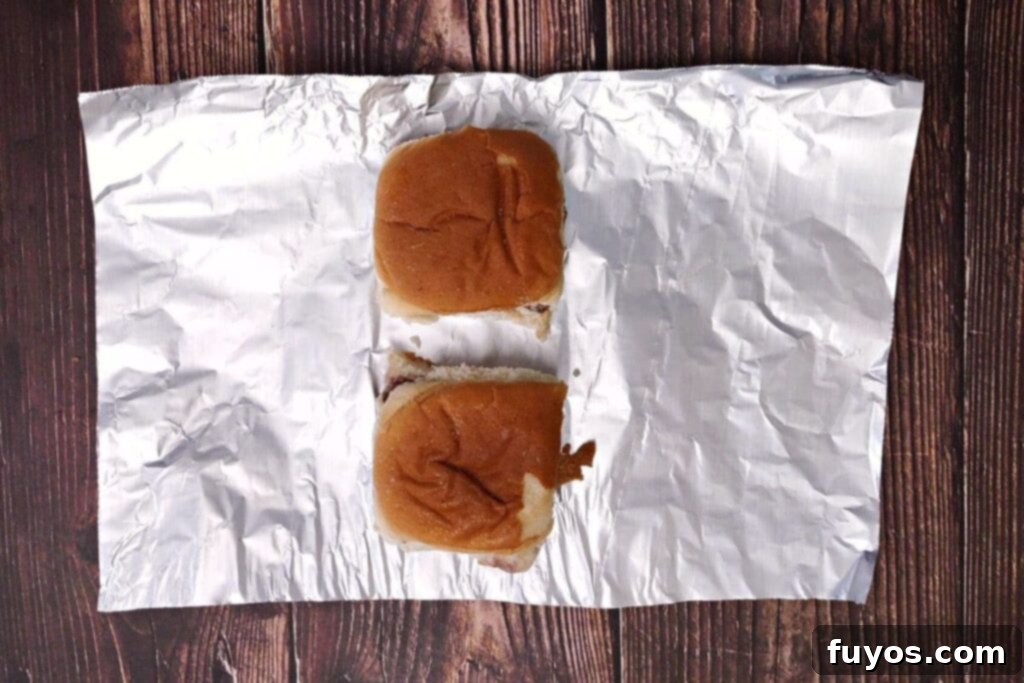 Quick and Easy Air Fried White Castle Sliders From Frozen 6 Placing frozen White Castle sliders onto aluminum foil, preparing for a protective wrap in the air fryer
