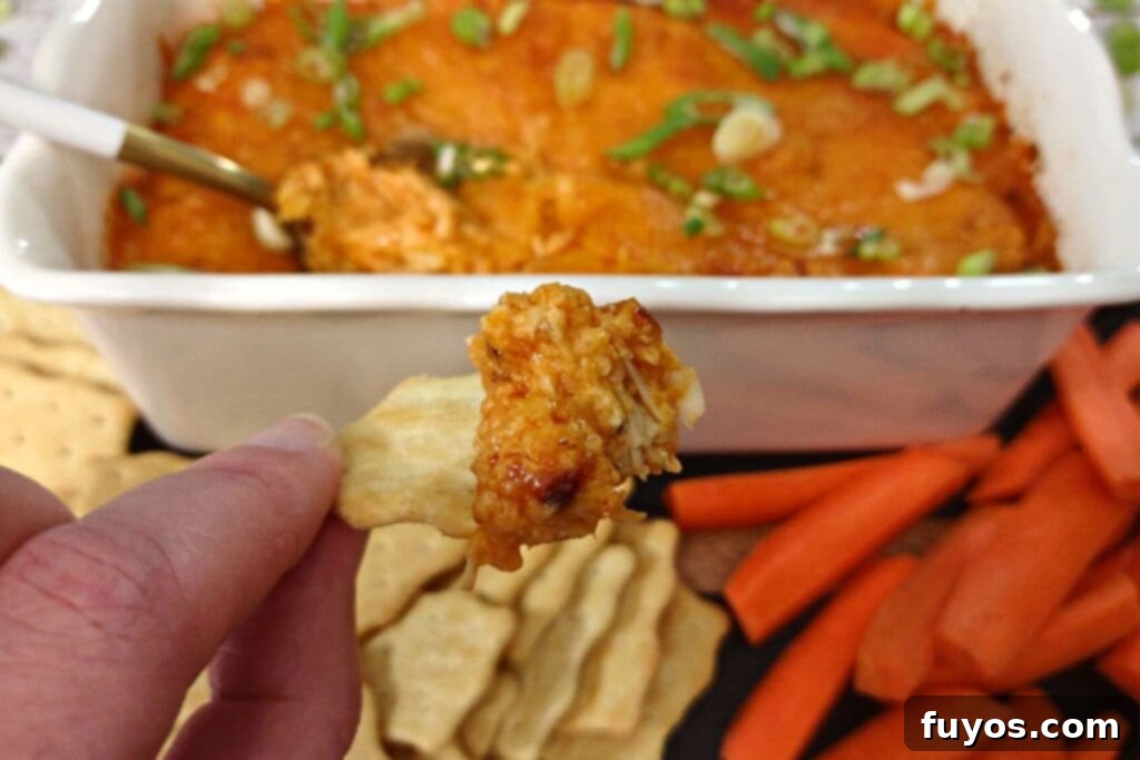 Ultimate Air Fryer Buffalo Chicken Dip 3 Scooped air fried buffalo chicken dip on a cracker with a golden brown top.