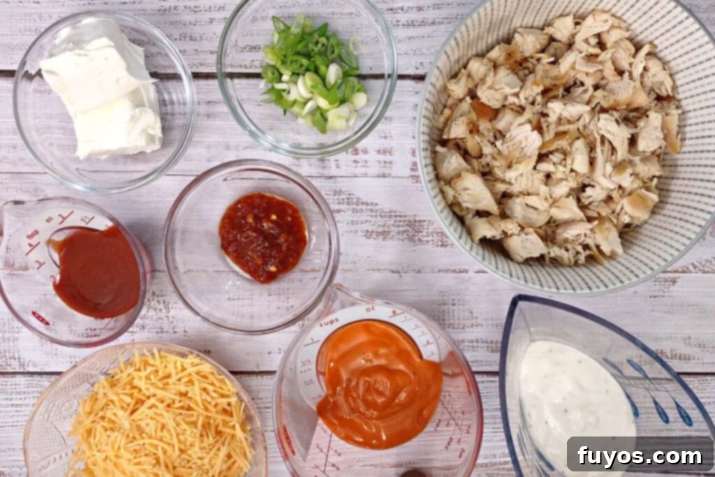 Ultimate Air Fryer Buffalo Chicken Dip 4 Ingredients laid out for making air fryer buffalo chicken dip, including cheese, chicken, sauces, and green onions.