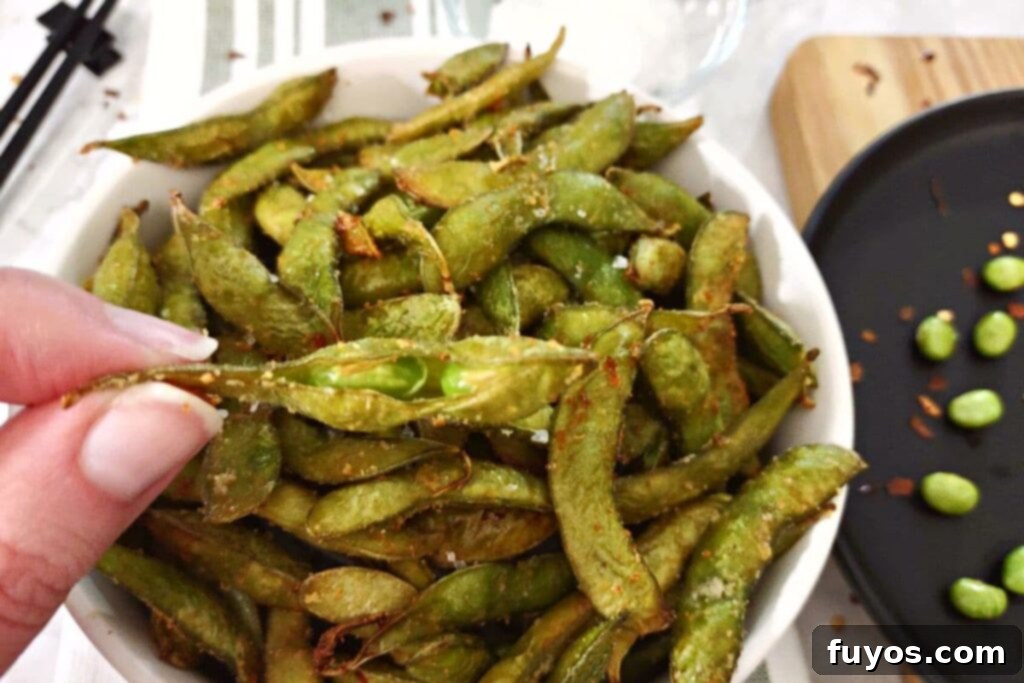 Holding up spicy garlic edamame from the air fryer