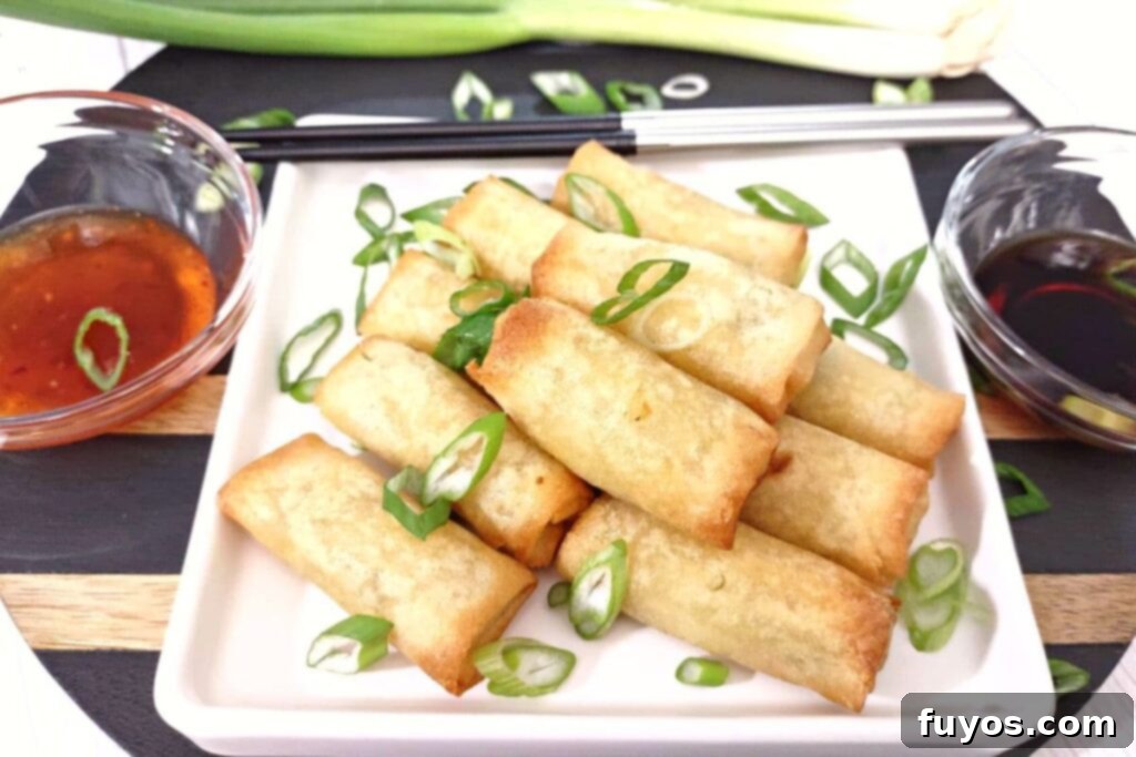 Crispy Air Fryer Spring Rolls in 5 Minutes 7 reheated air fryer spring rolls stacked on a plate with dipping sauces on the site