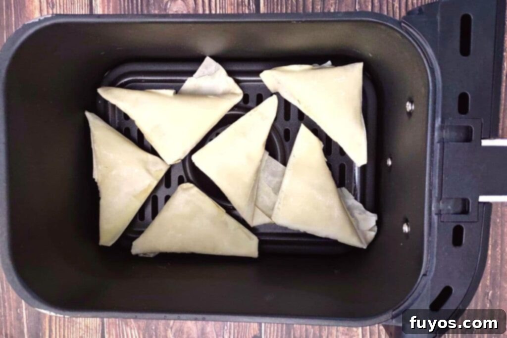 Trader Joe's Spanakopita Air Fryer Crispy Snack 5 Trader Joe's spanakopita triangles arranged in a single layer within an air fryer basket