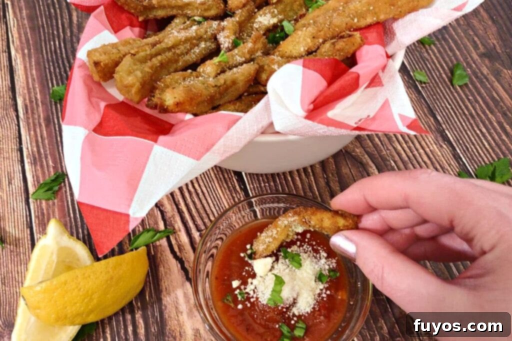 dipping an air fried eggplant fry in marinara