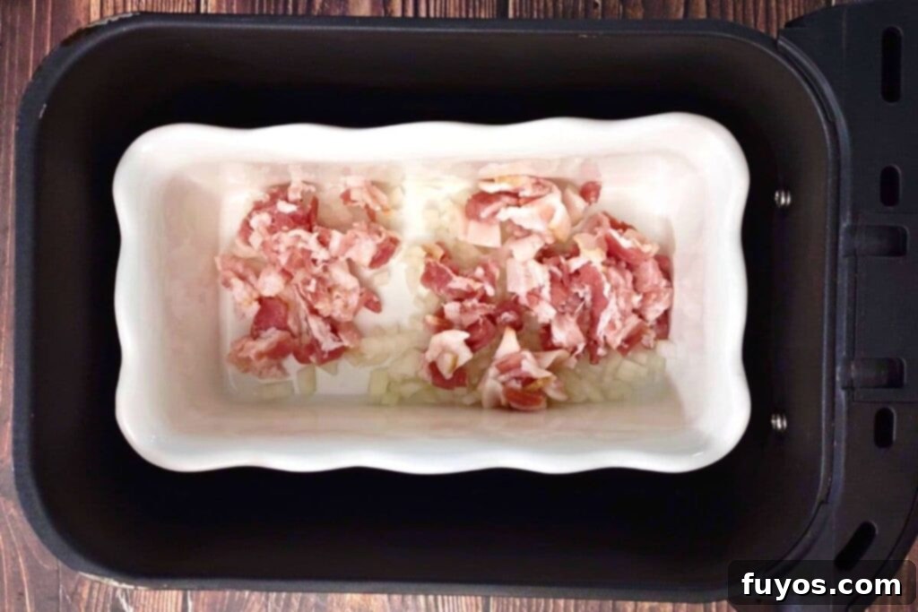 Cooking bacon and onion in the air fryer basket for baked beans