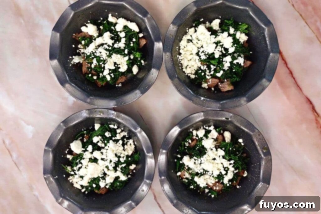 add steak, spinach, and feta cheese to mini quiche pans