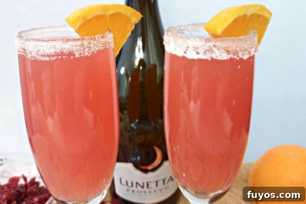 Cranberry Orange Mimosa Brunch Celebration 3 Closeup of two sparkling cranberry orange mimosas in elegant flutes, with a bottle of Prosecco in the background, highlighting the vibrant colors and bubbles