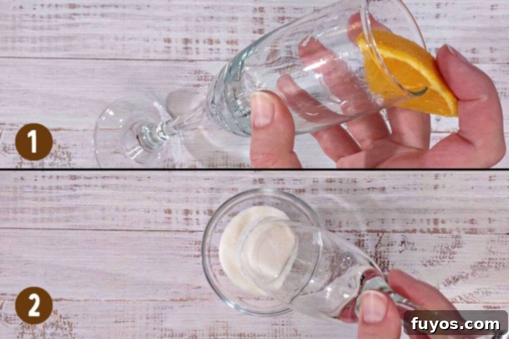 Cranberry Orange Mimosa Brunch Celebration 7 Step-by-step image showing how to create a sugar rim for a mimosa glass by rubbing an orange slice on the rim and then dipping it into granulated sugar