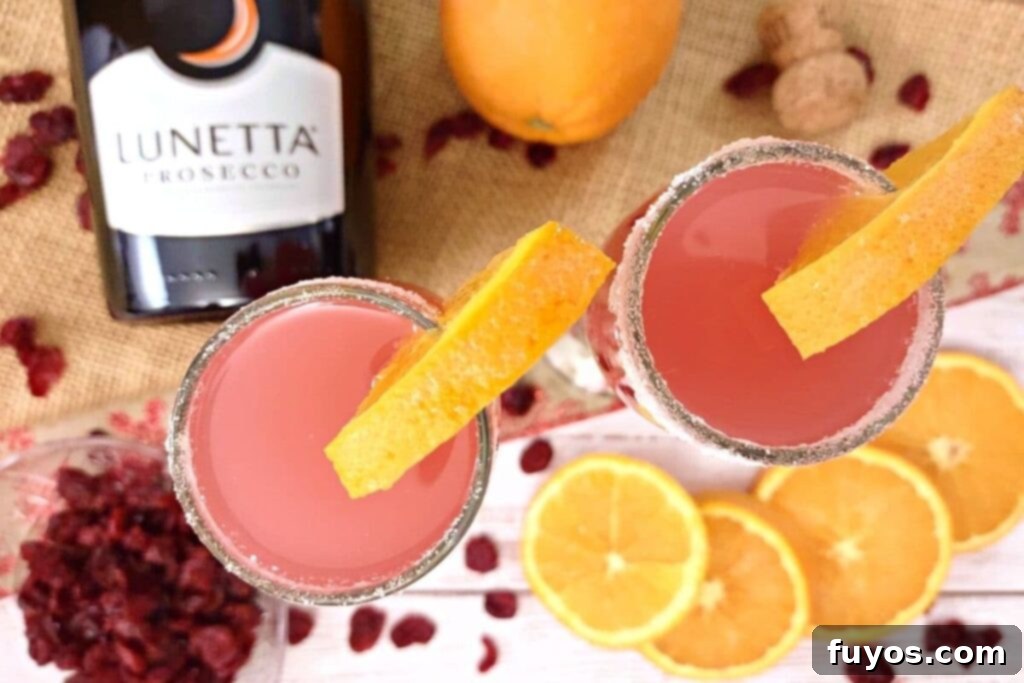Cranberry Orange Mimosa Brunch Celebration 8 Overhead view of two beautifully garnished cranberry orange mimosas in flutes, surrounded by fresh orange slices and loose cranberries, ready to serve