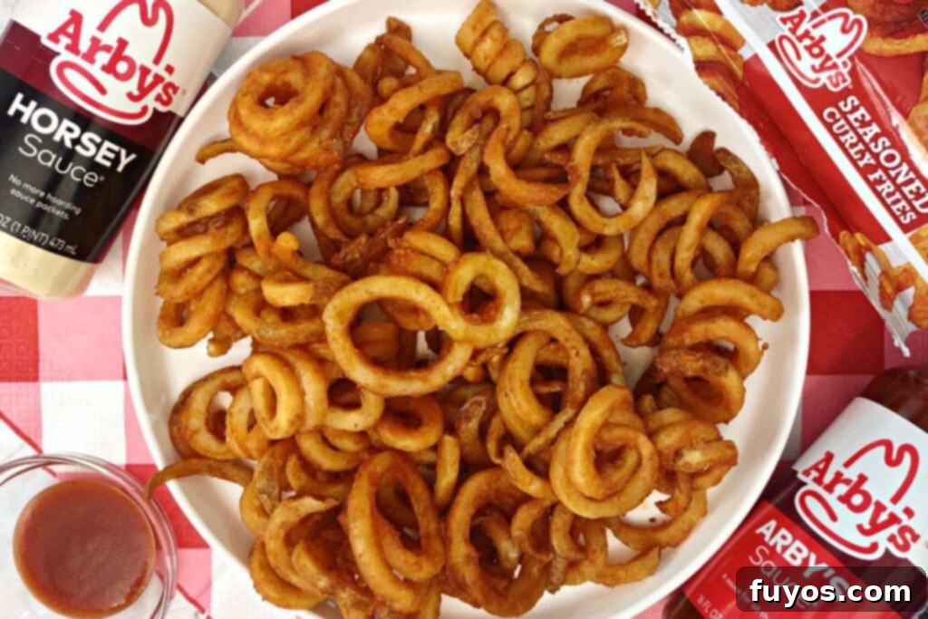 An overhead shot of hot, crispy Arby's curly fries artfully arranged on a white plate, ready to be served.