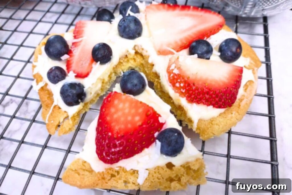 slice cut from a sugar cookie fruit pizza with strawberry and blueberry