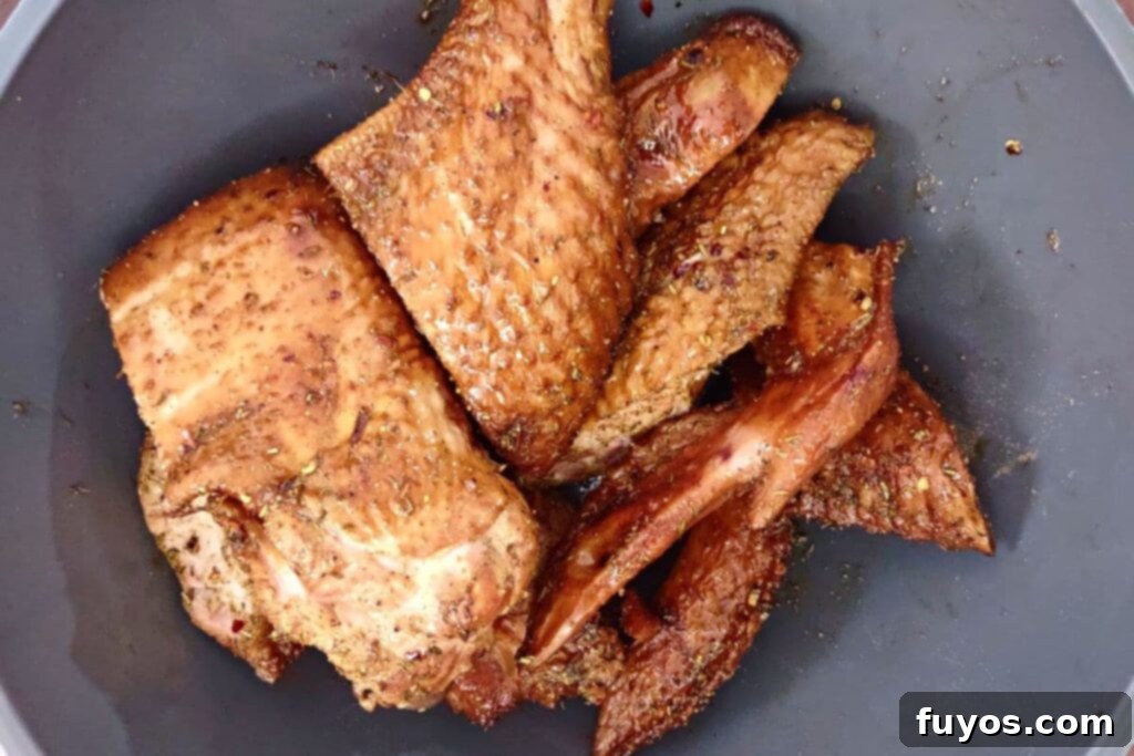 Tossing smoked turkey wings with olive oil and seasoning in a bowl
