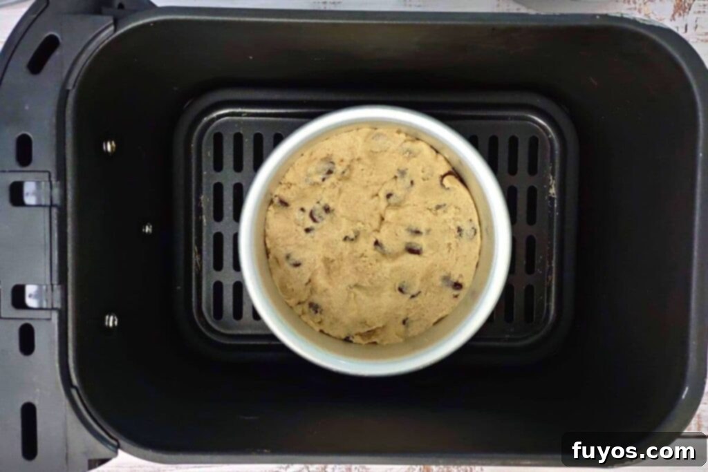 A pan with cookie dough placed in an air fryer basket, ready for cooking