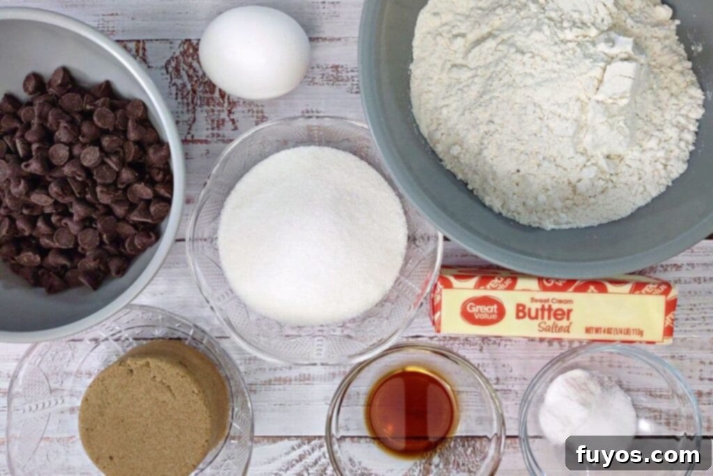 Collection of fresh ingredients arranged on a countertop, including butter, sugars, eggs, flour, and chocolate chips, ready for making air fryer cookie cake