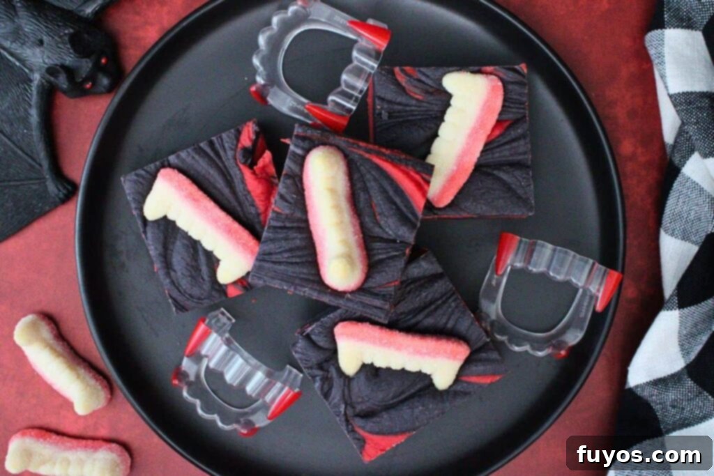 Vampire Fudge: A Sinfully Simple Halloween Indulgence 9 An overhead shot of perfectly cut vampire fudge squares arranged on a black plate, garnished with gummy worms and fangs, highlighting the festive Halloween theme.