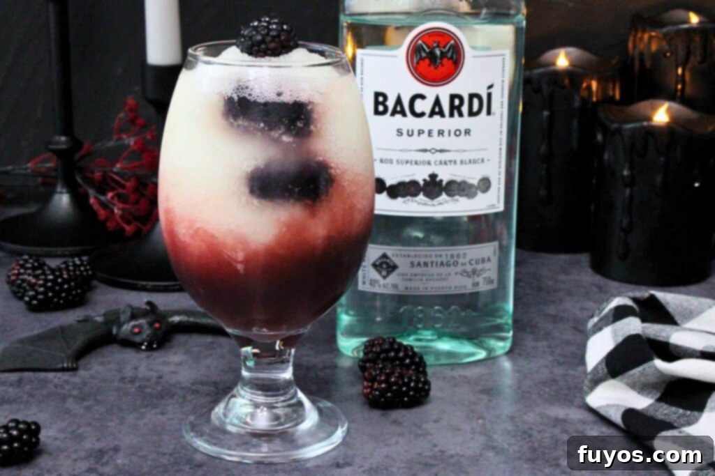 Make Your Own Dracula Juice for Halloween 3 Copycat Applebee's Dracula Juice cocktail next to a rum bottle, surrounded by bats and dark Halloween decorations, enhancing the spooky theme.