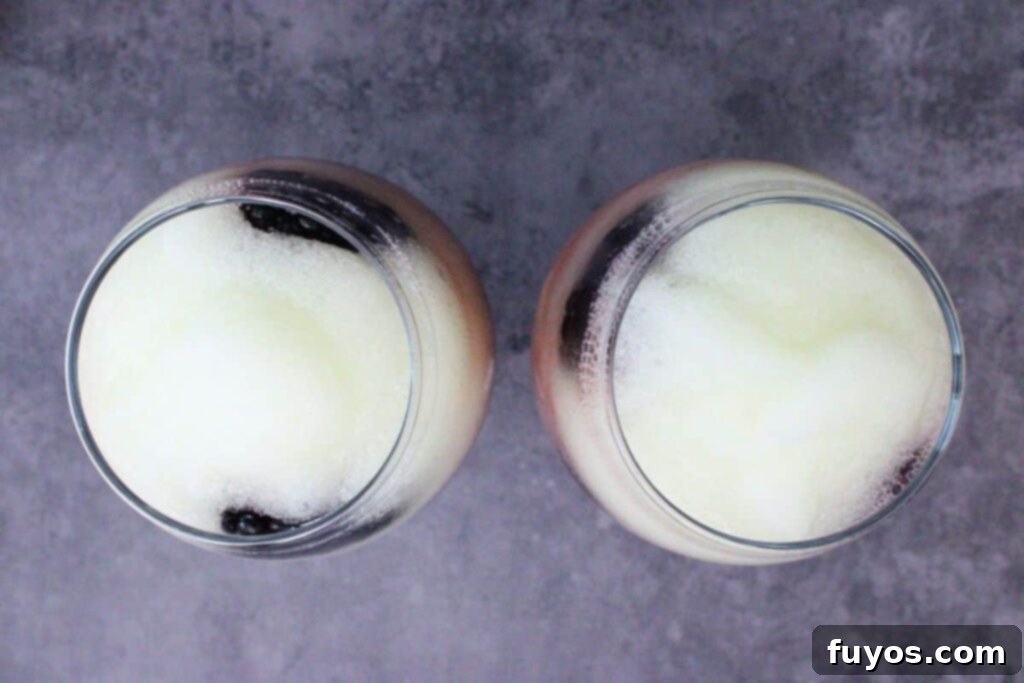 Make Your Own Dracula Juice for Halloween 7 Slowly pouring the slushy lemonade layer over the red juice mixture, with blackberries placed along the glass edge for layering.